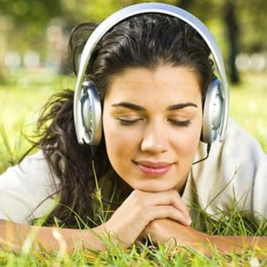 Pige med hovedtelefoner på liggende i græsset